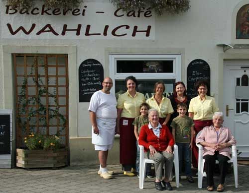 Team der Bäckerei-Café Wahlich posiert vor dem Eingang mit zwei älteren Damen und Kindern