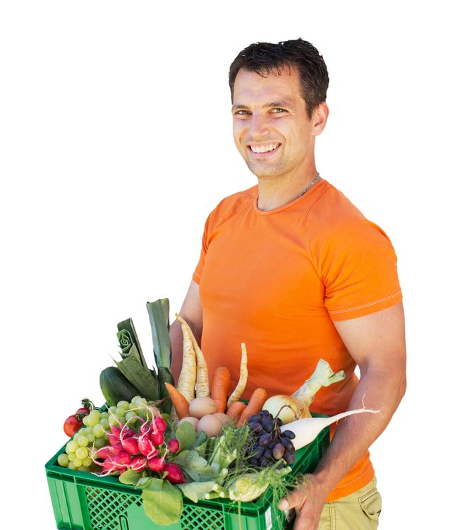 Mann im orangenen T-Shirt trägt Kiste mit frischem Gemüse und Obst und lächelt
