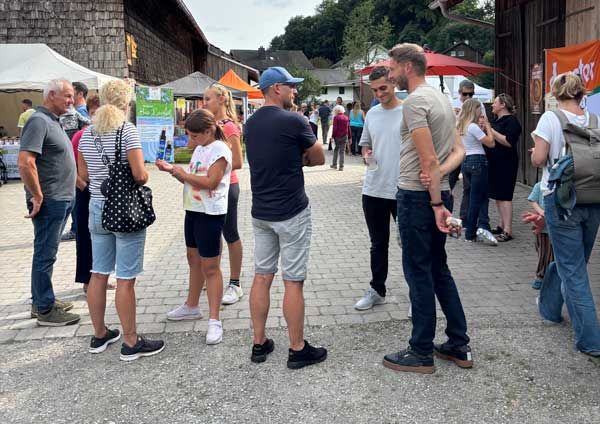 Menschen unterschiedlicher Altersgruppen stehen im Freien und unterhalten sich bei einer Veranstaltung.