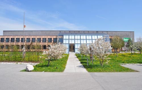 Moderne Bürogebäude mit Glasfassade, blühenden Bäumen und klar blauem Himmel im Frühling
